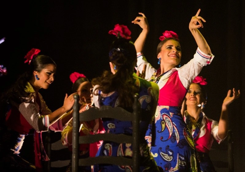 Grupo de bailaoras con trajes de colores y flores